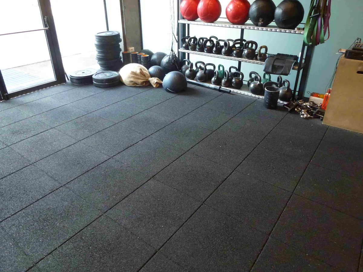 Zona de entrenamiento con pesas rusas y suelo ECO-GYM de losas negras